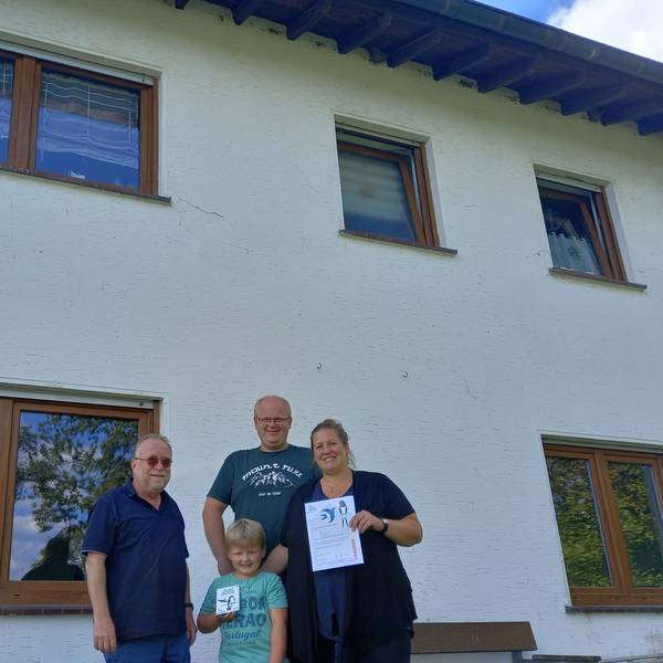 Christoph Buchen (links), Vorsitzender der Nabu-Ortsgruppe in der Gemeinde Morsbach, überreicht Katja Eichmann und Kevin Brast mit Sohn Ole Urkunde und Plakette für ihr schwalbenfreundliches Haus in der Ortschaft Wallerhausen.