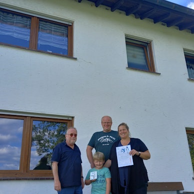Christoph Buchen (links), Vorsitzender der Nabu-Ortsgruppe in der Gemeinde Morsbach, überreicht Katja Eichmann und Kevin Brast mit Sohn Ole Urkunde und Plakette für ihr schwalbenfreundliches Haus in der Ortschaft Wallerhausen.