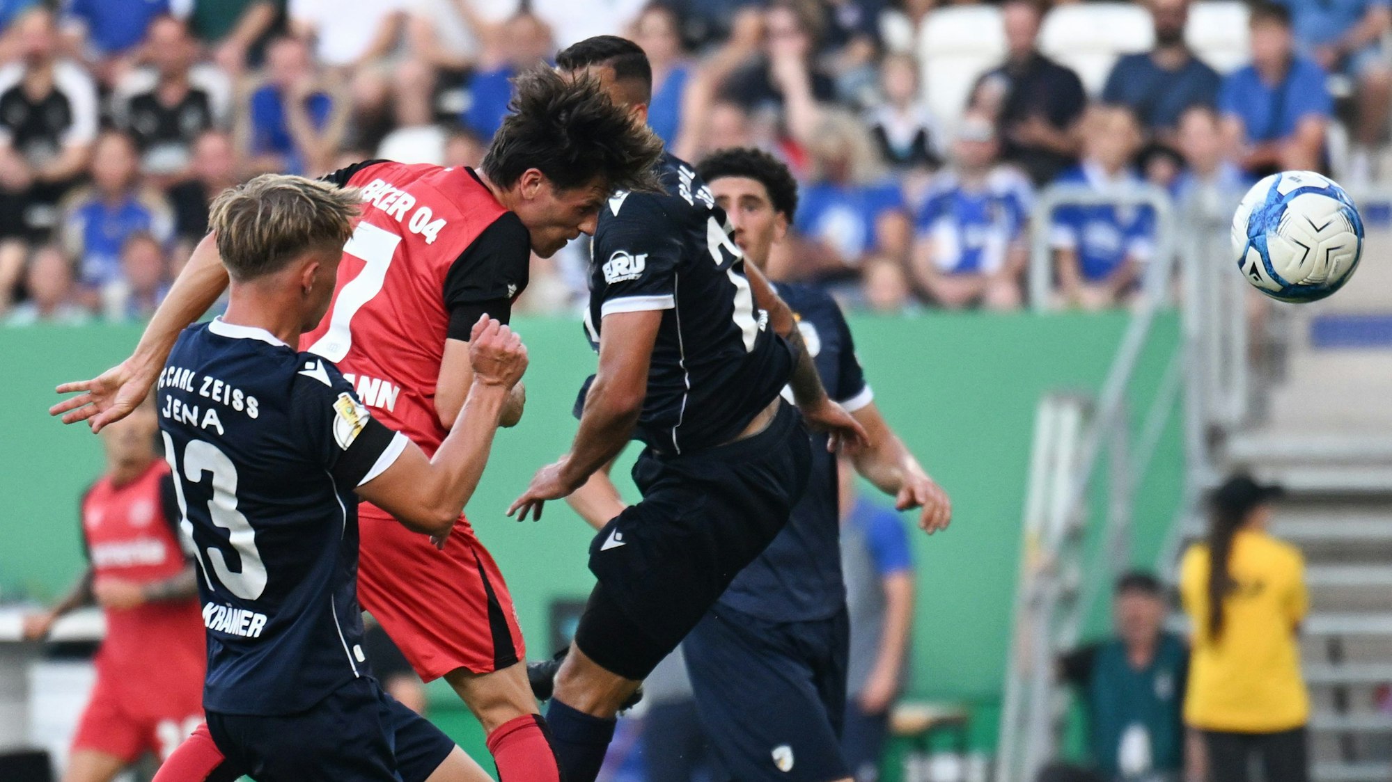 28.08.2024, Thüringen, Jena: Fußball: DFB-Pokal, FC Carl Zeiss Jena - Bayer 04 Leverkusen, 1. Runde, Ernst-Abbe-Sportfeld. Leverkusens Jonas Hofmann (M) setzt sich gegen Jenas Spieler Paul Krämer (l) und Justin Schau durch und erzielt den Treffer zum 0:1. Foto: Hendrik Schmidt/dpa - WICHTIGER HINWEIS: Gemäß den Vorgaben der DFL Deutsche Fußball Liga bzw. des DFB Deutscher Fußball-Bund ist es untersagt, in dem Stadion und/oder vom Spiel angefertigte Fotoaufnahmen in Form von Sequenzbildern und/oder videoähnlichen Fotostrecken zu verwerten bzw. verwerten zu lassen. +++ dpa-Bildfunk +++