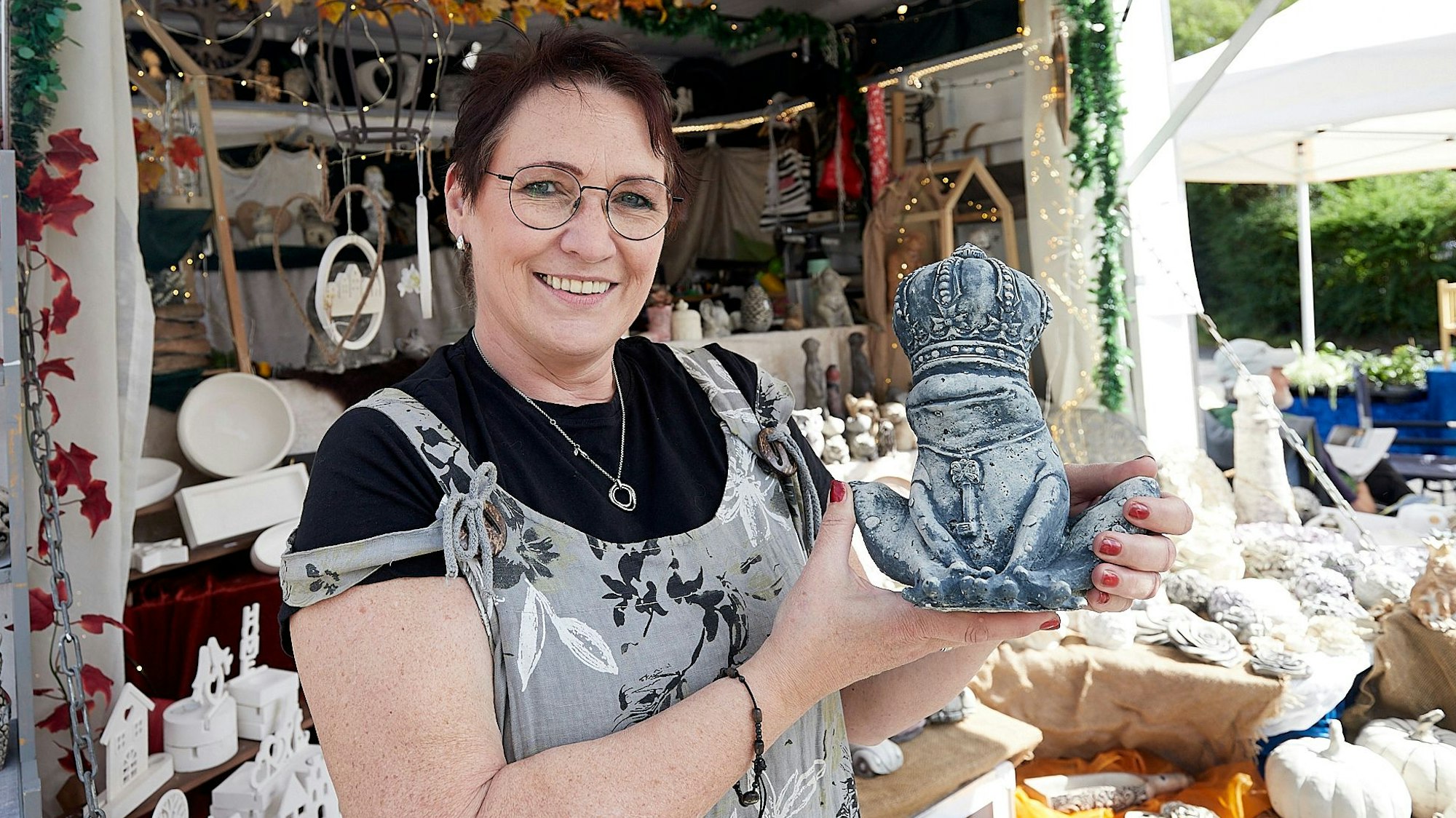Pia Benz steht an ihrem Verkaufswagen und hält eine von ihr angefertigte Figur aus Beton in den Händen.