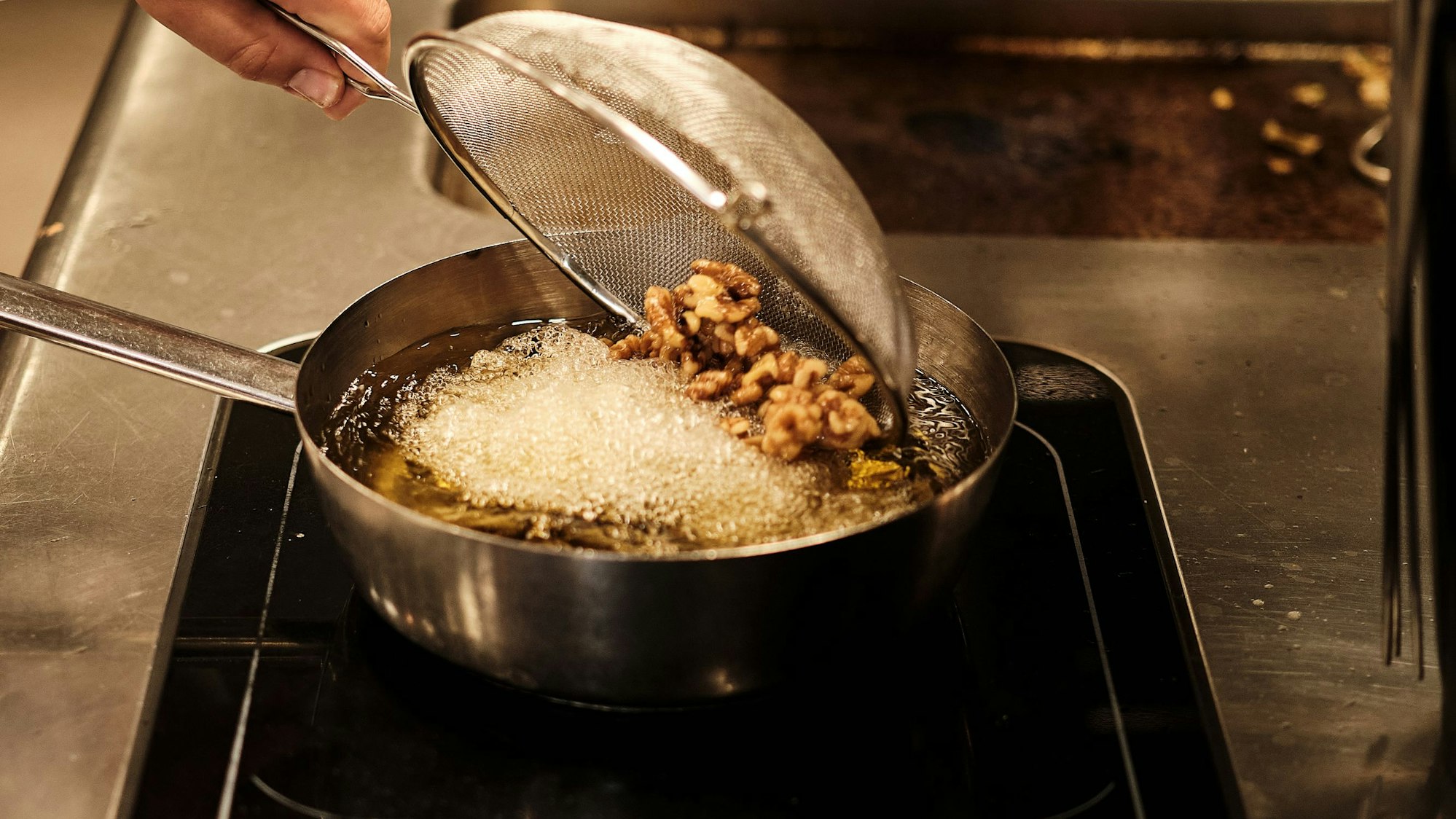 Walnüsse in ein Sieb abgießen, abtropfen lassen, ins heiße Frittierfett geben und 1 Minute karamellisieren, bis sie goldbraun sind.