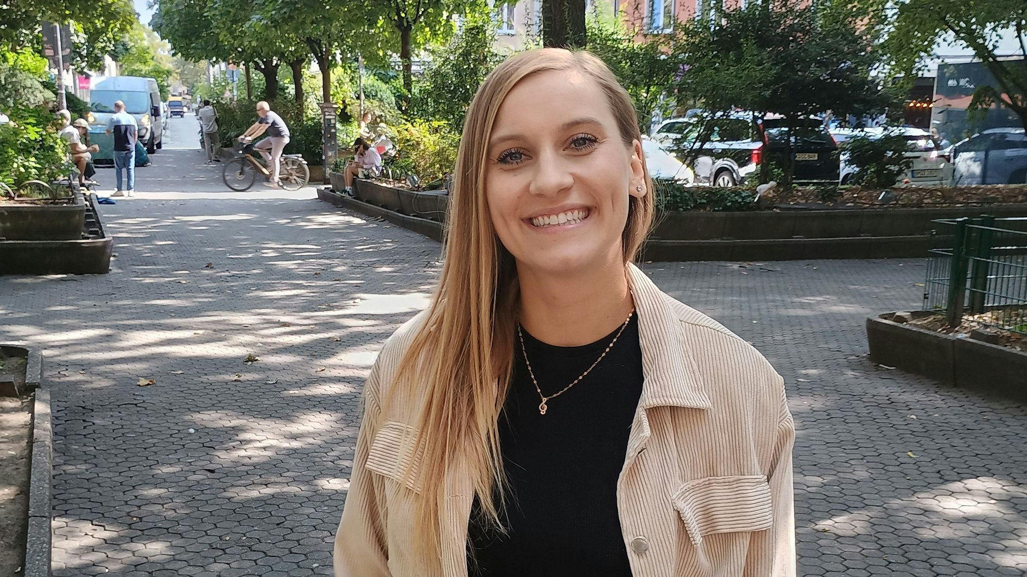 Eine blonde Frau steht auf einem Platz.