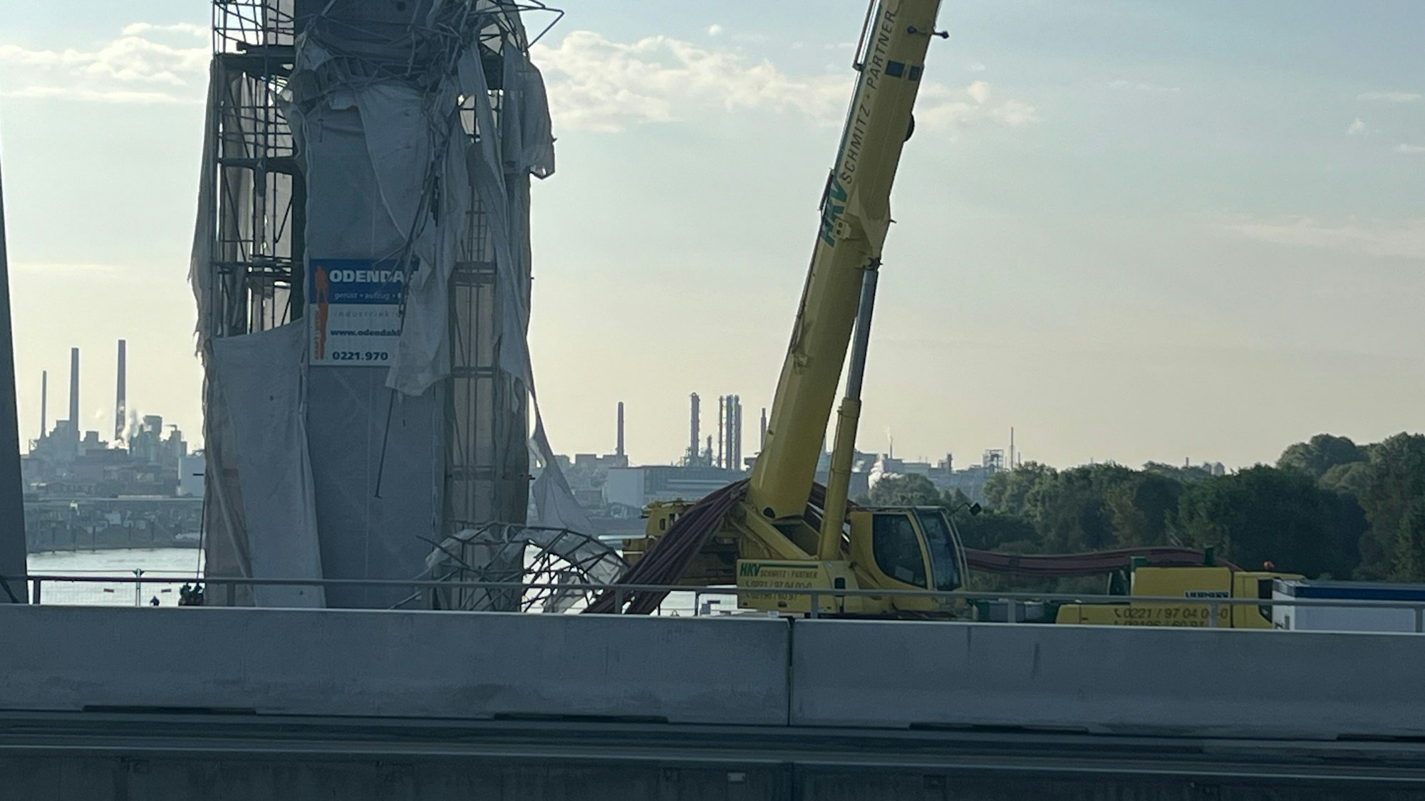 Ein Kran steht neben einem teilweise abgerissenen Brückenpfeiler am Rhein.