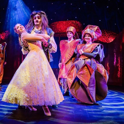 Zu sehen sind Theaterschauspieler auf der Bühne bei einer Aufführung von „Die Schöne und das Biest“.