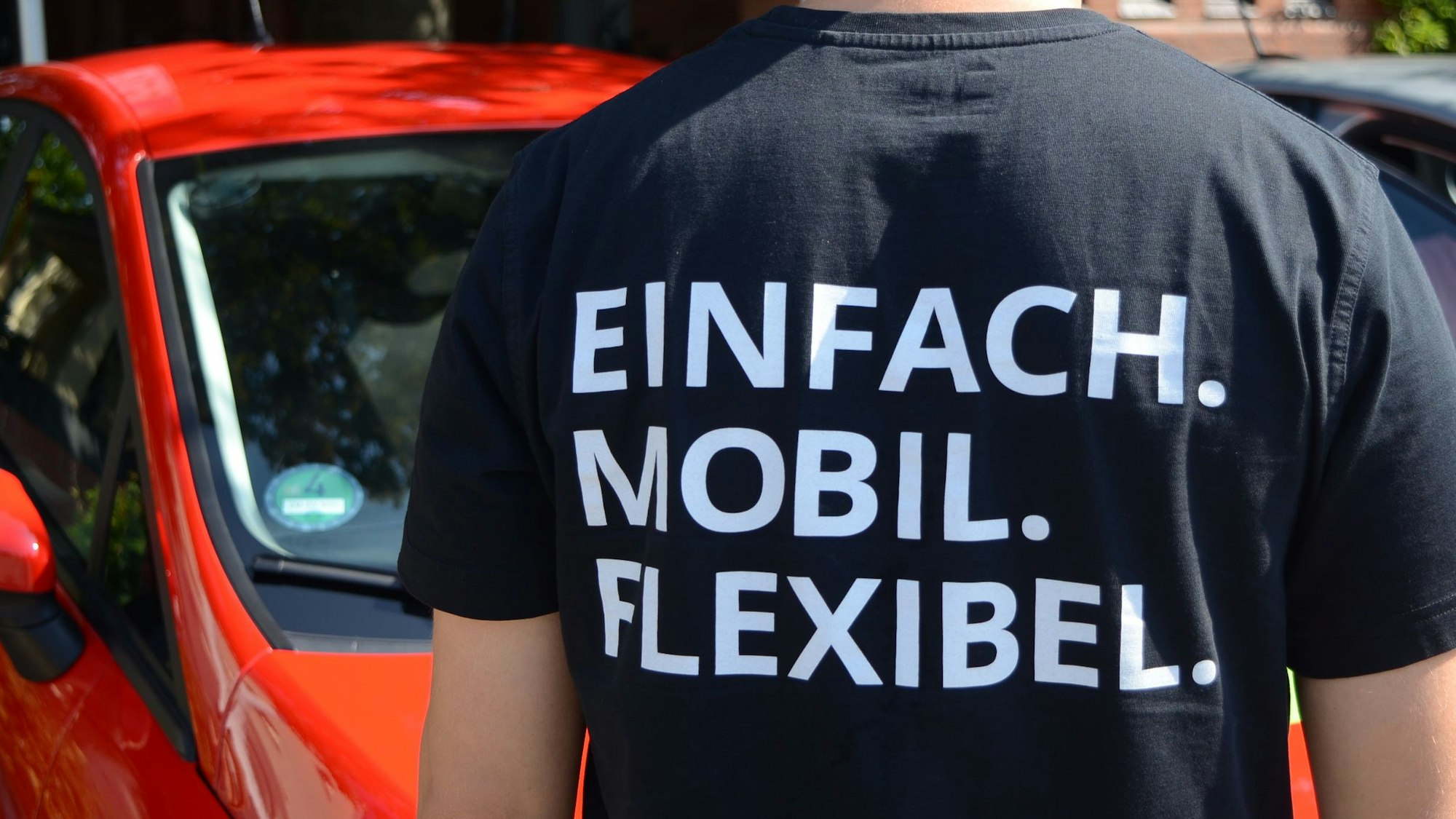 Ein Mann im schwarzen T-Shirt von hinten. Auf dem T-Shirt steht Einfach. Mobil. Flexibel.