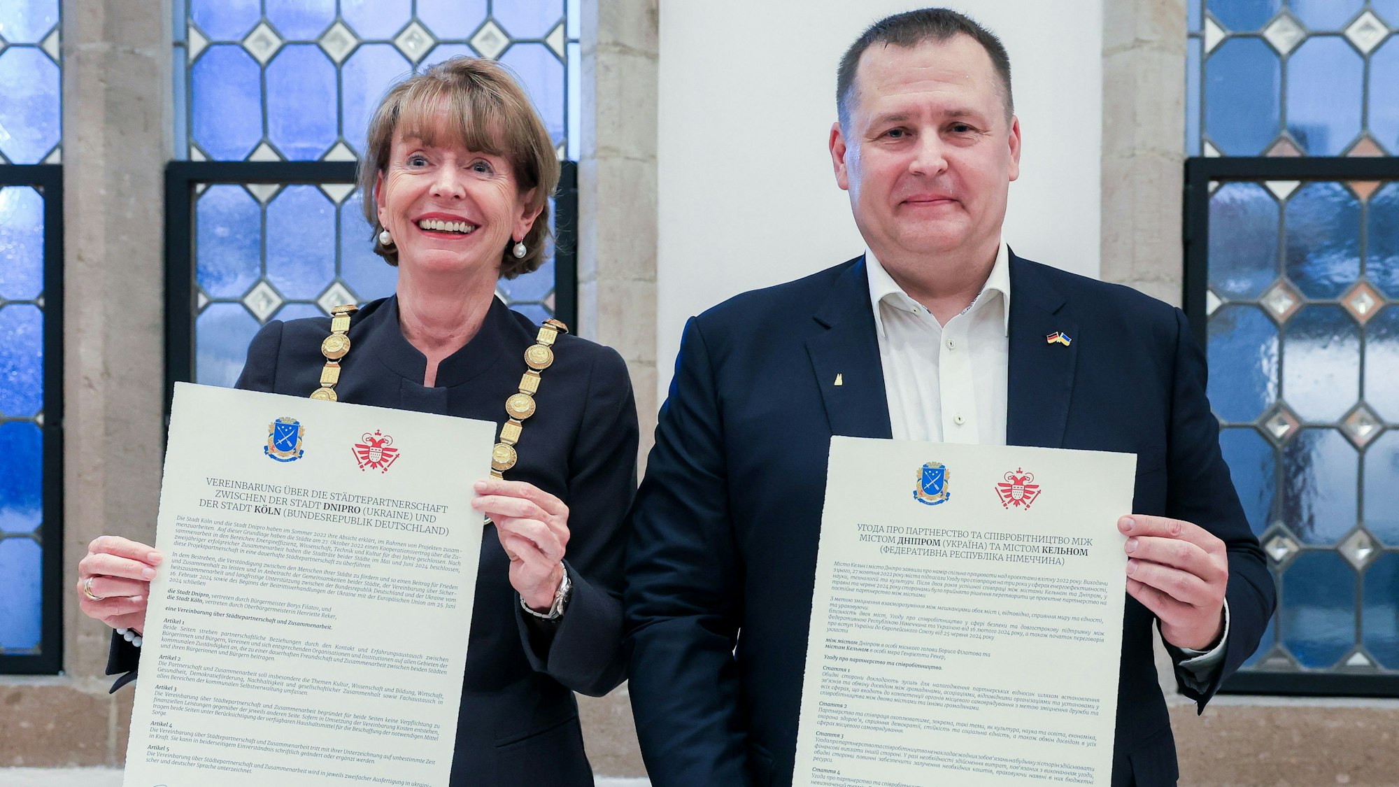Zu sehen ist Henriette Reker mit Dnipros Bürgermeister Boris Filatov, die Urkunden in den Hälten halten, in der Vorderansicht.