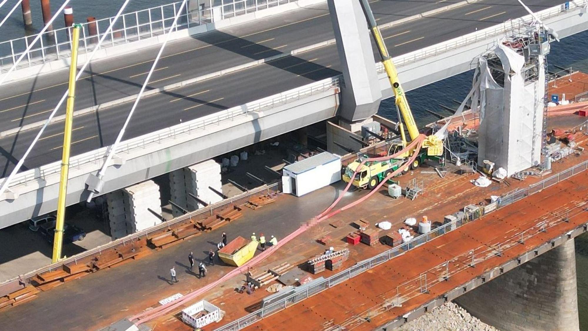 Bei Abrissarbeiten des alten Brückenbauteils durch den Autokran geschah das Unglück. Der Kran wurde durch die abgestürzten roten Tragseile der Brücke beschädigt.
