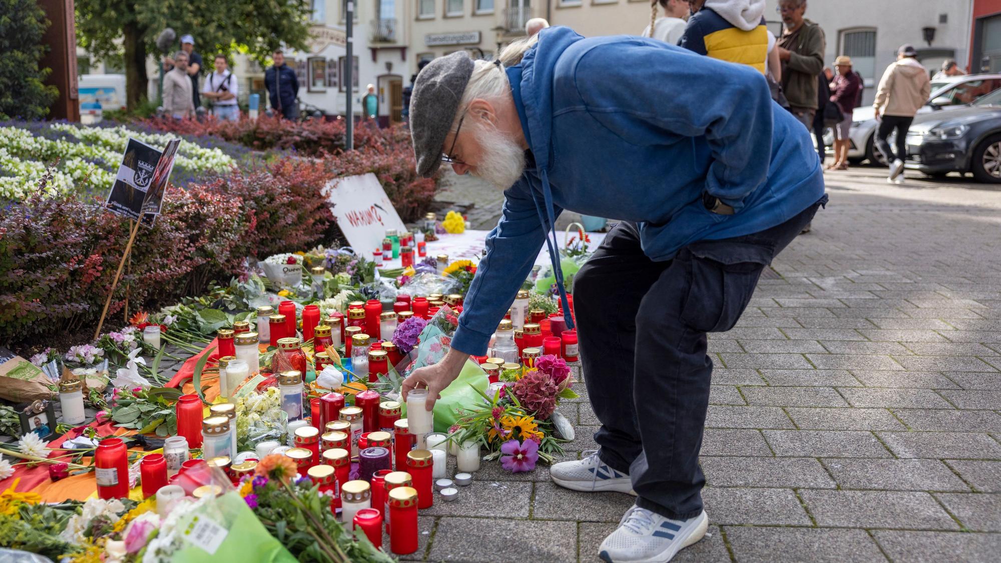 Solingen: Der Organisator der Jubiläums-Feier stellt im Gedenken an die Opfer eine Kerze auf.