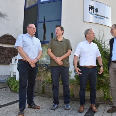 Vier Männer stehen vor dem Oberbergischen Kreishaus beisammen.