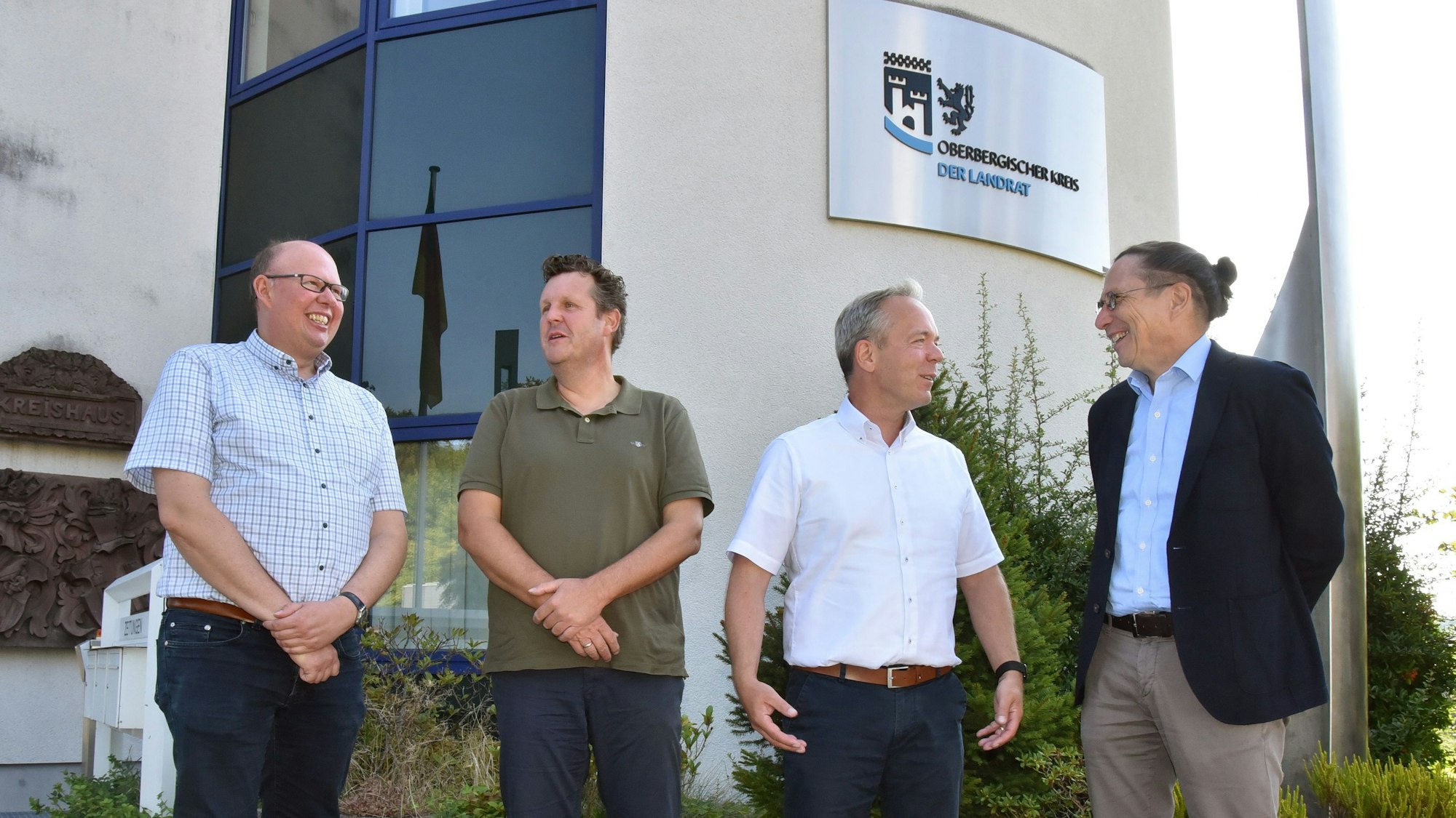 Vier Männer stehen vor dem Oberbergischen Kreishaus beisammen.