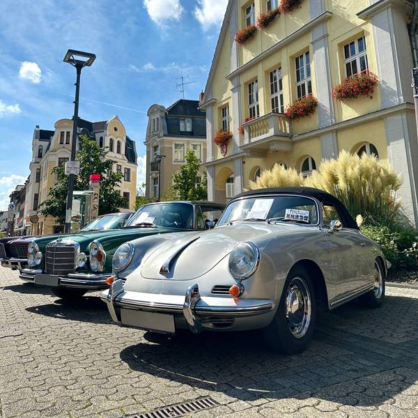 Auf dem Bild sind ein grüner und ein grauer Oldtimer zu sehen.