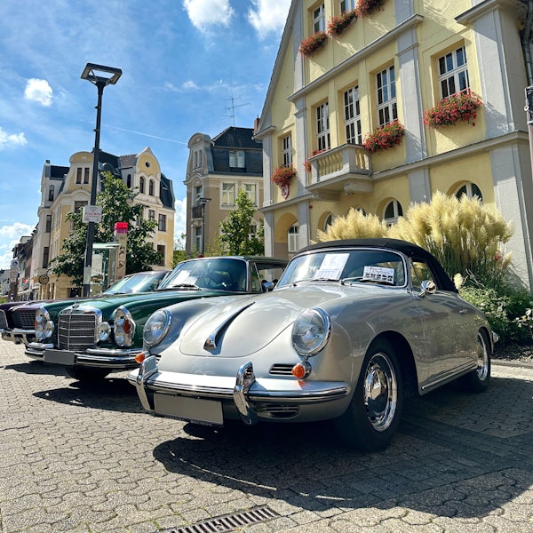 Auf dem Bild sind ein grüner und ein grauer Oldtimer zu sehen.