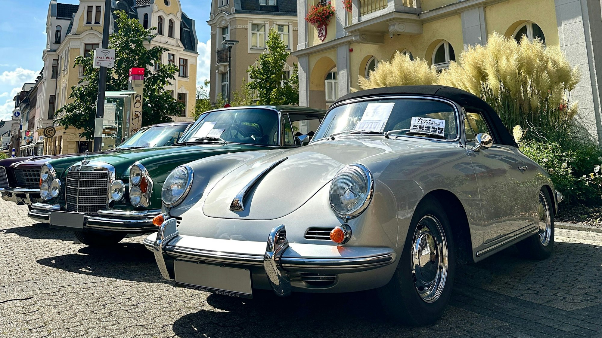 Auf dem Bild sind ein grüner und ein grauer Oldtimer zu sehen.