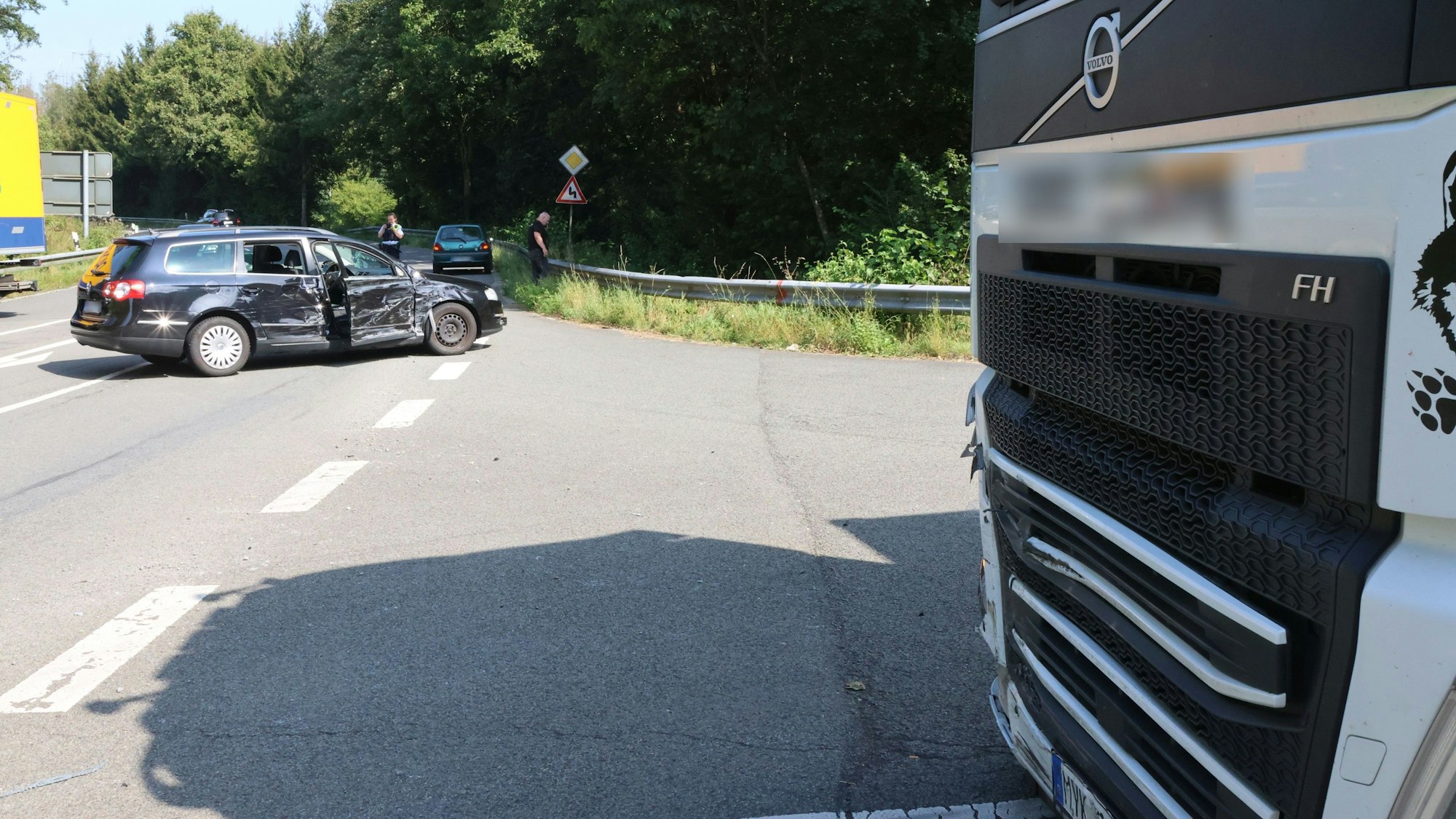 Ein Pkw steht nach einem Unfall quer auf der Straße. Im Hintergrund ist ein Lkw zu sehen, der in den Unfall verwickelt war.