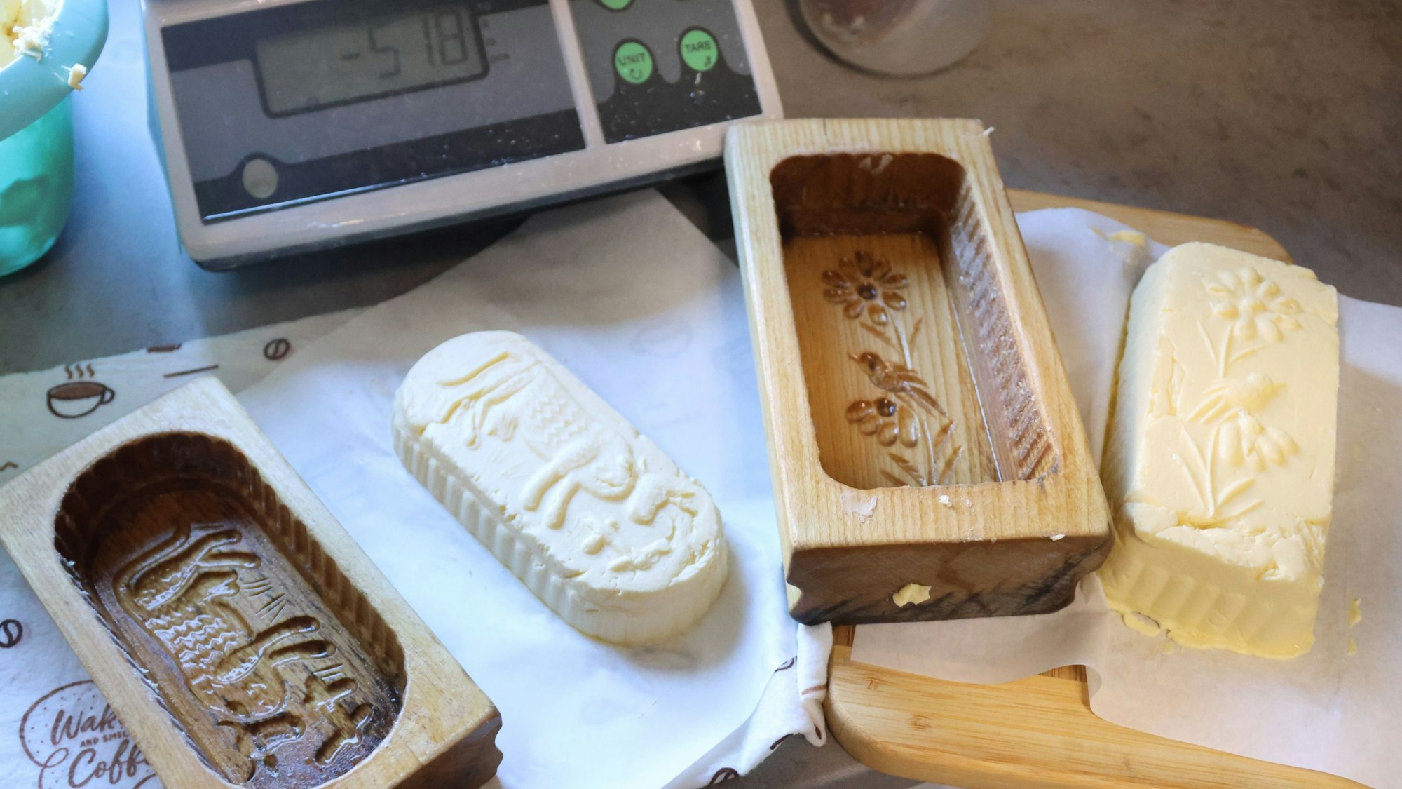 Die noch weiche Butter streicht Sabine Greb in hölzerne Formen mit Blumen- und Kuh-Dekor. Dabei wird die Masse gewogen und für den Verkauf als halbes oder ganzes Pfund vorbereitet.