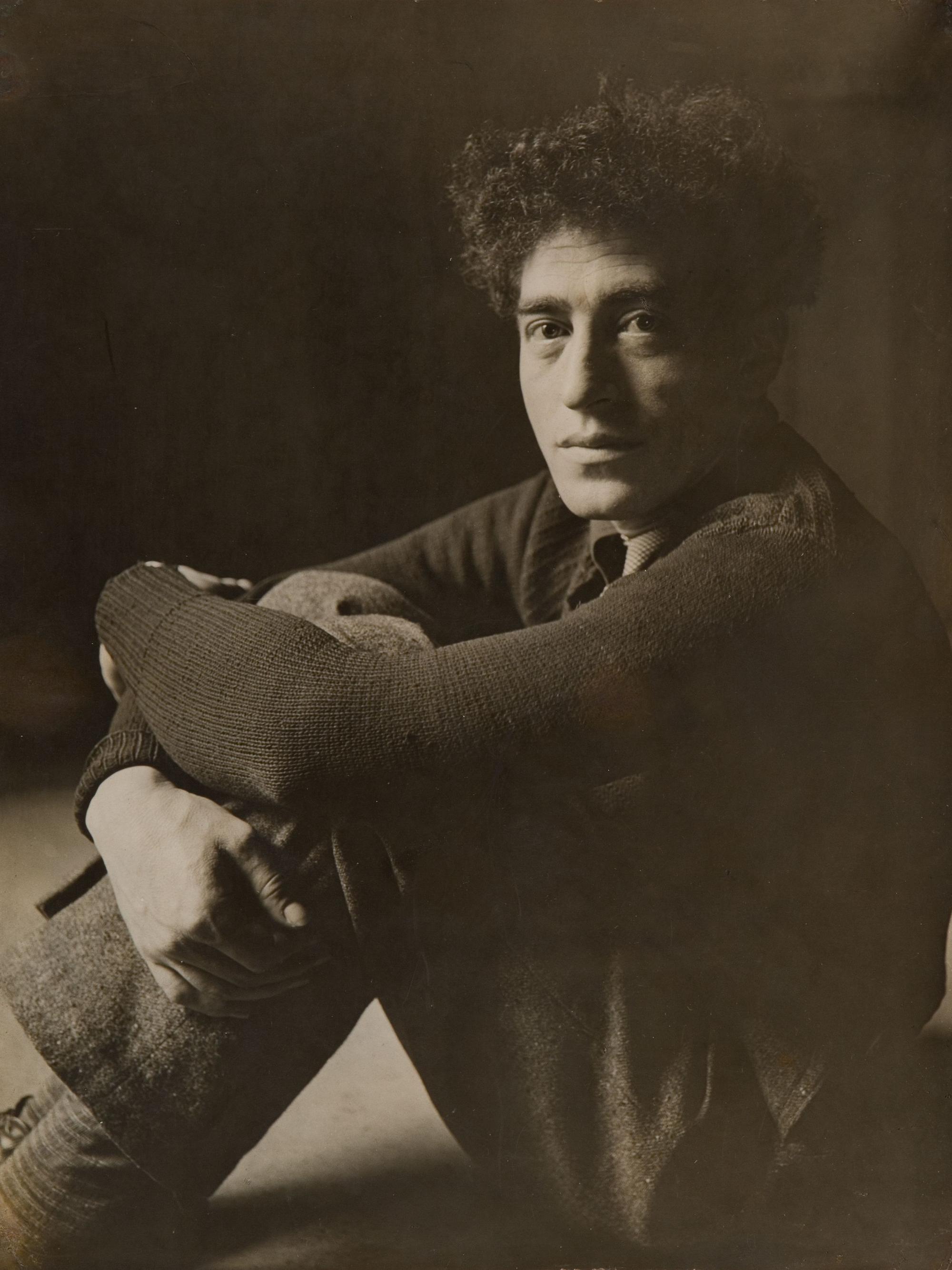 Alberto Giacometti sitzt mit angezogenen Beinen auf dem Boden.