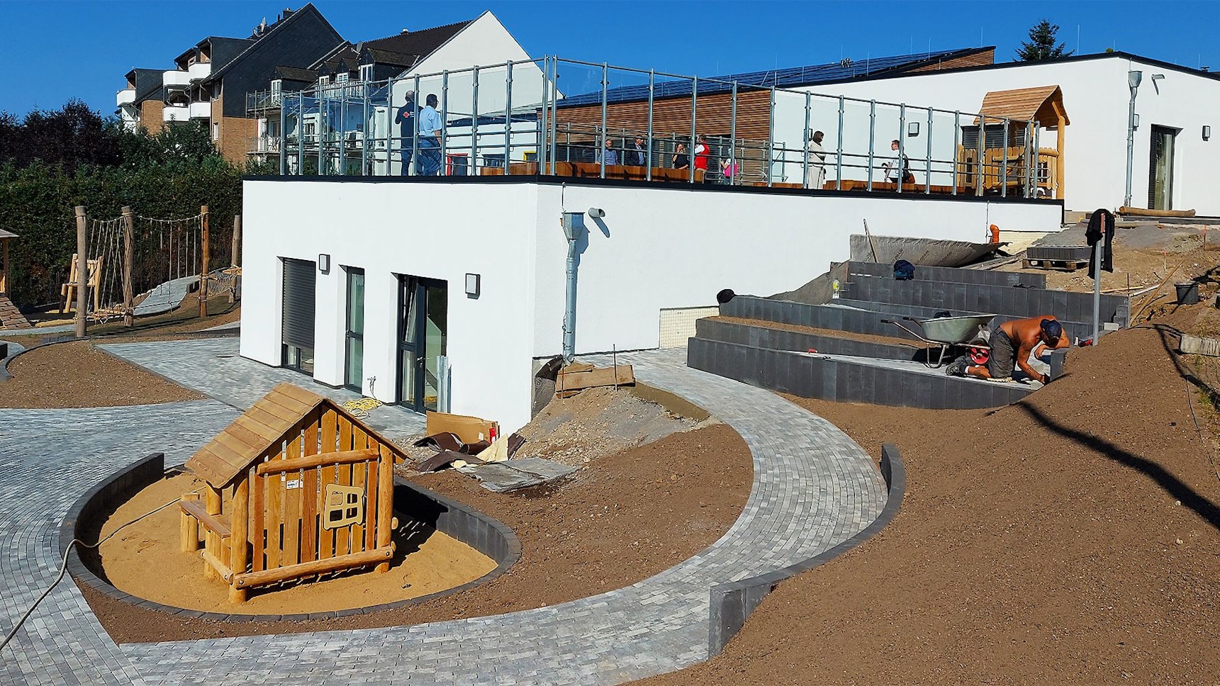 Auf dem Außengelände einer Kita arbeitet ein Handwerker.