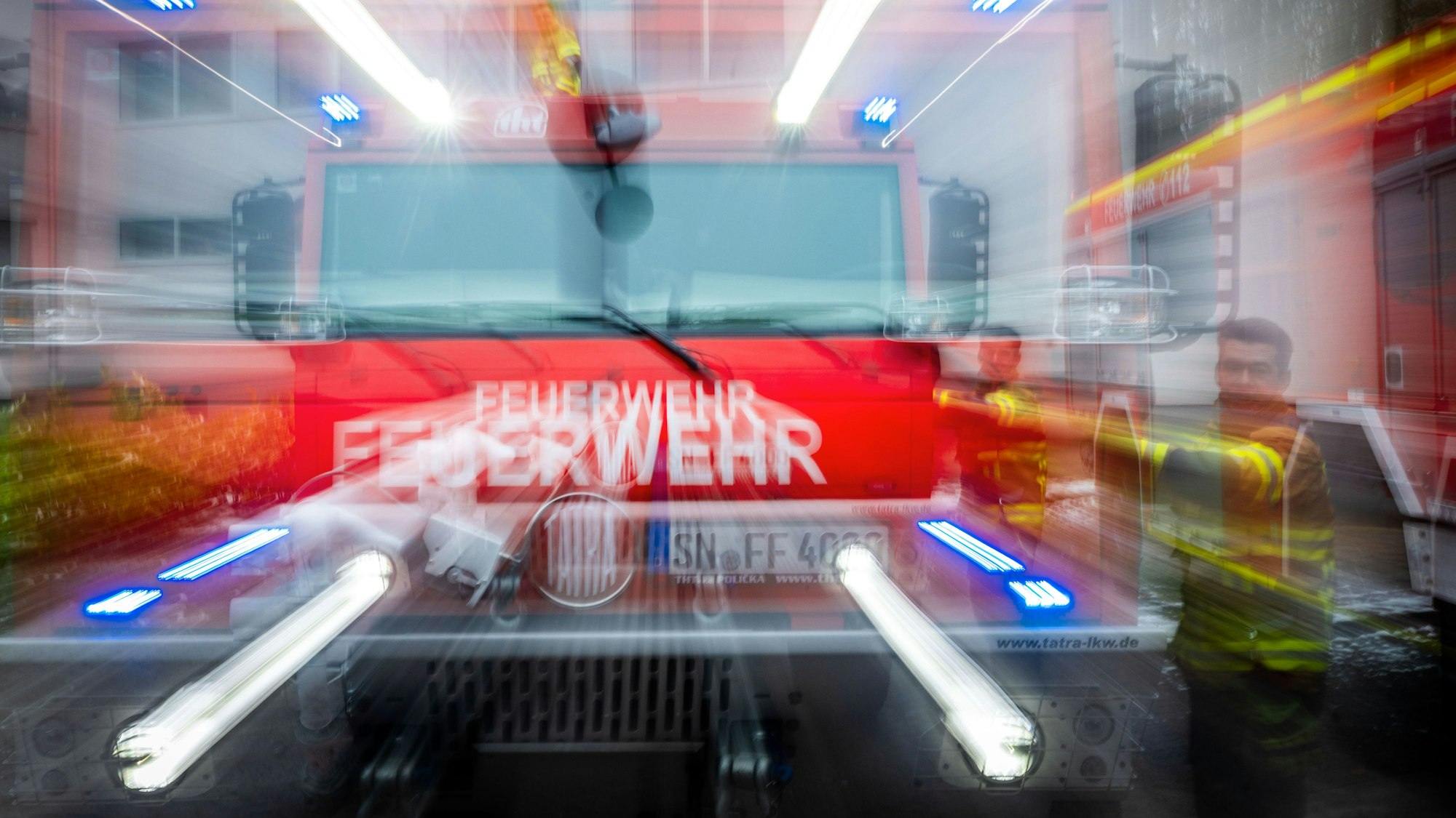 Ein Löschfahrzeug der Feuerwehr spiegelt sich frontal in einer Scheibe.