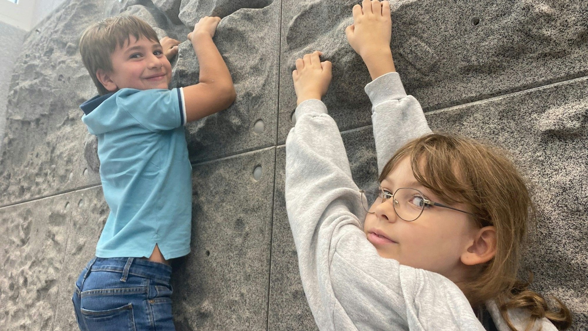 Zu sehen sind zwei Grundschüler an einer Kletterwand.