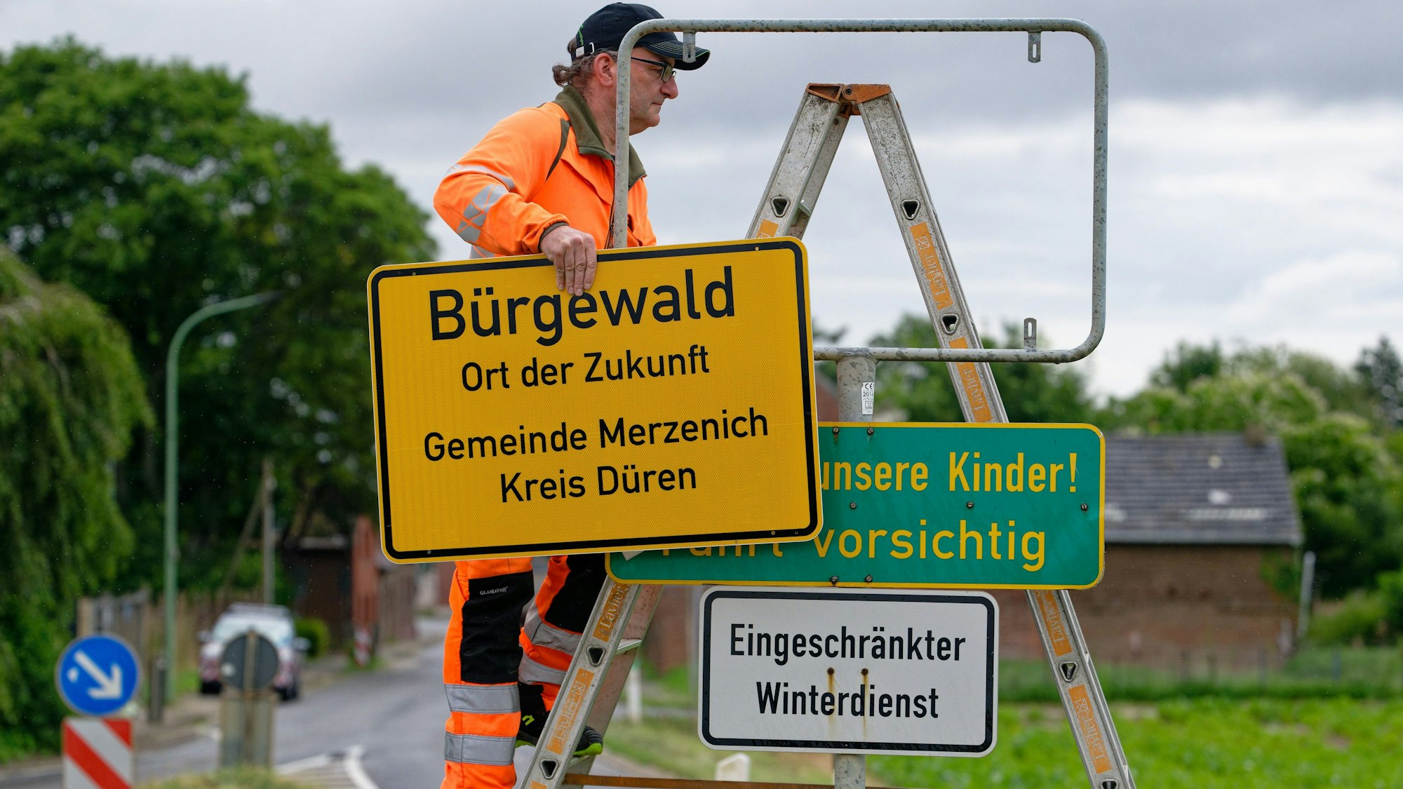 Ein Mitarbeiter von Straßen NRW bringt ein neues Ortsschild am Ortseingang des Braunkohledorfes Morschenich an.