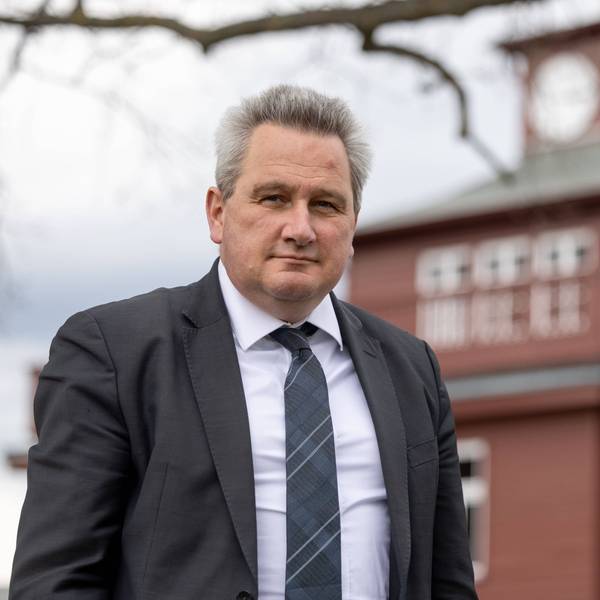 Jens-Christian Wagner, Direktor der Stiftung Gedenkstätten Buchenwald und Mittelbau-Dora in Thüringen, steht vor der einem Gebäude der Gedenkstätte. Er trägt einen dunklen Anzug und ein weißes Hemd.