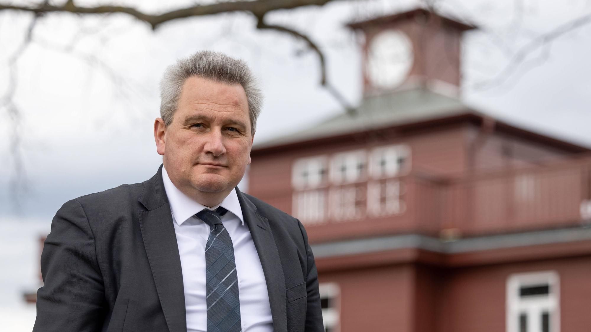 Jens-Christian Wagner, Direktor der Stiftung Gedenkstätten Buchenwald und Mittelbau-Dora in Thüringen, steht vor der einem Gebäude der Gedenkstätte. Er trägt einen dunklen Anzug und ein weißes Hemd.