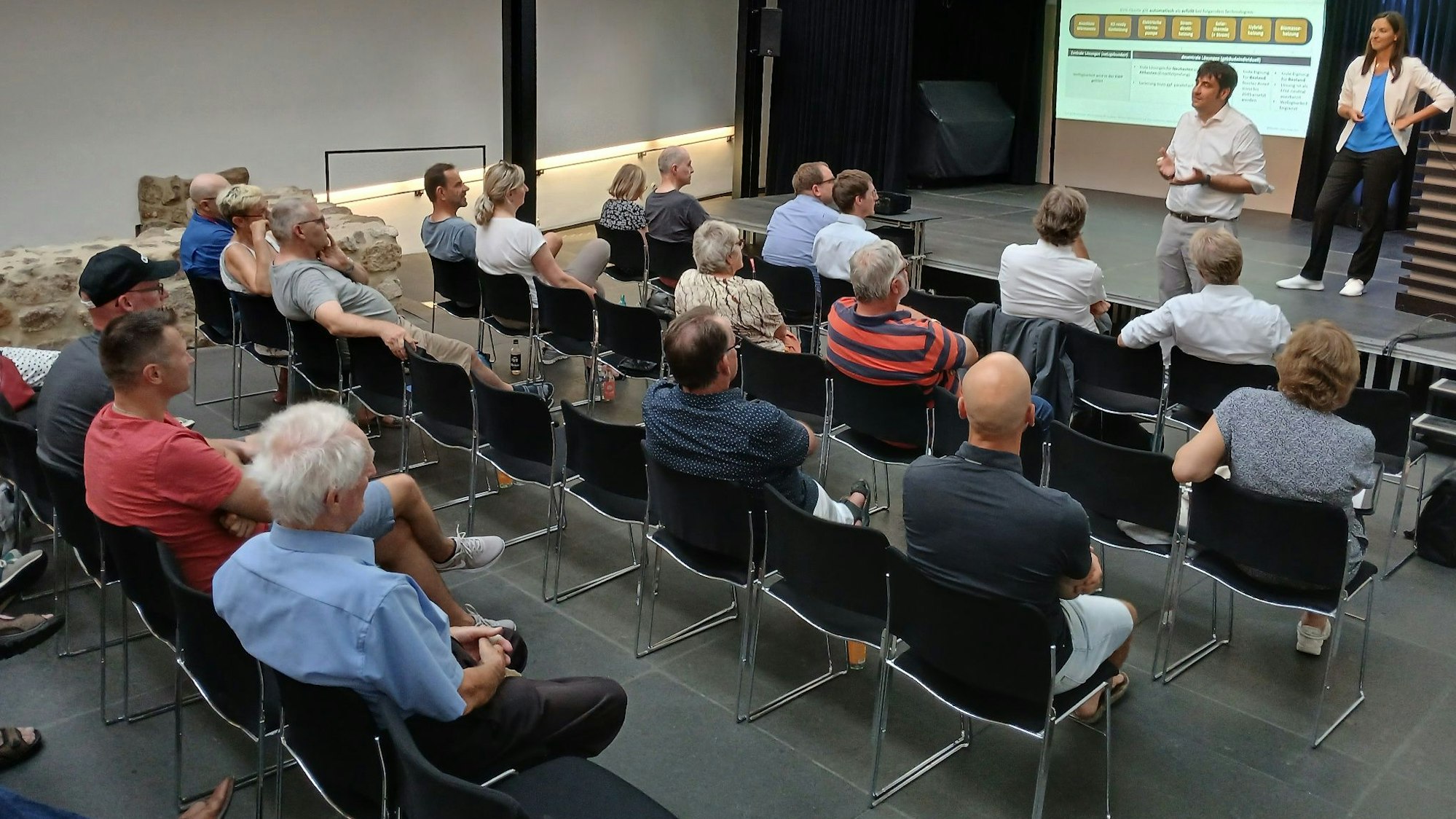 Menschen auf Stühlen bei einer Informationsveranstaltung.