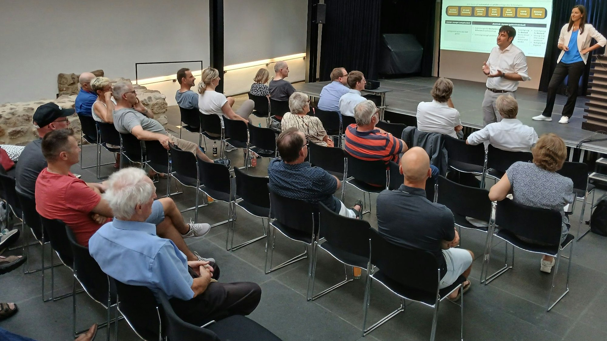 Menschen auf Stühlen bei einer Informationsveranstaltung.