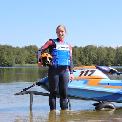 Bild einer jungen Frau vor einem Jetski an einem See