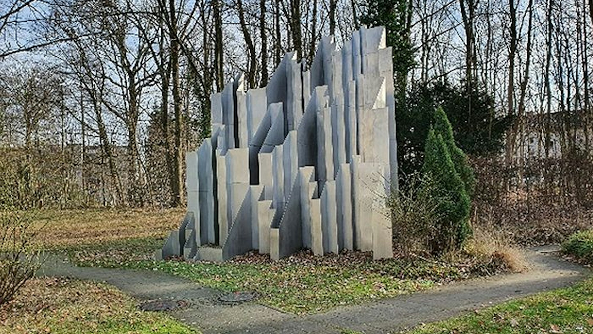 Eine Skulptur steht vor Bäumen in einem Park.