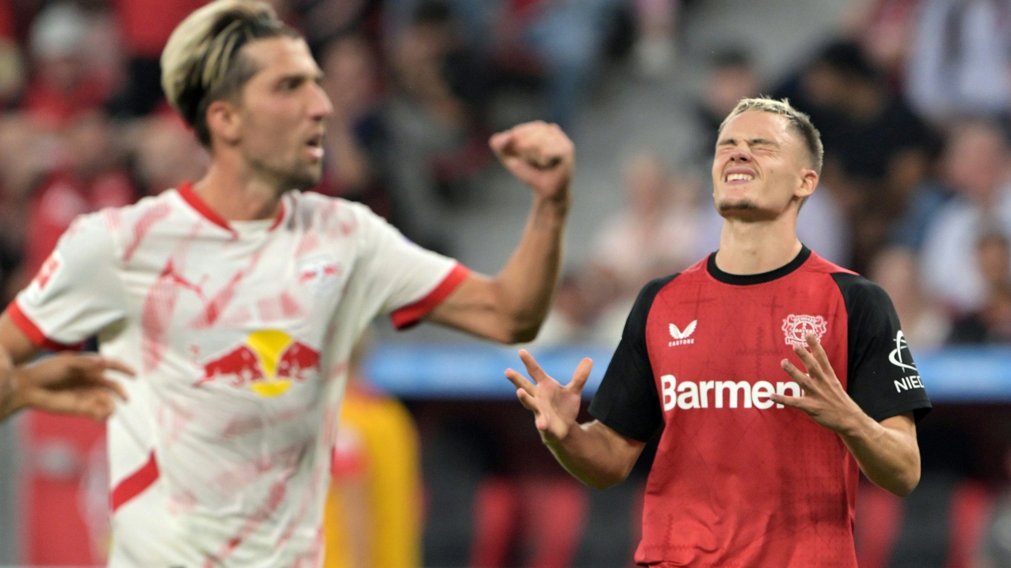 Leverkusens Florian Wirtz (r) und Leipzigs Kevin Kampl reagieren auf dem Feld.