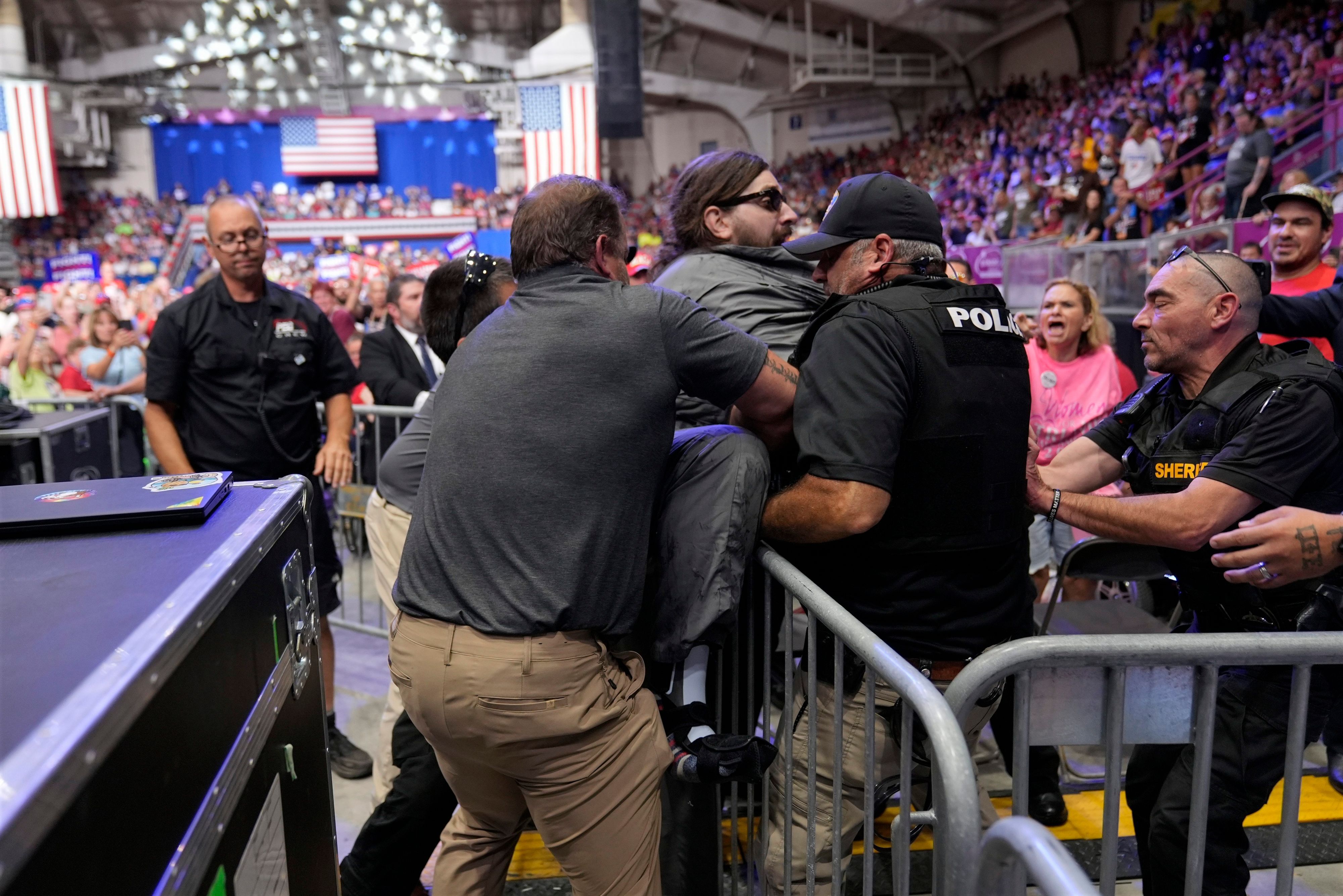 Die Polizei entfernt einen Mann (Mitte), der auf das Podium geklettert ist, als der republikanische US-Präsidentschaftskandidat und ehemalige US-Präsident Trump auf einer Wahlkampfveranstaltung in Johnstown, Pennsylvania, spricht.