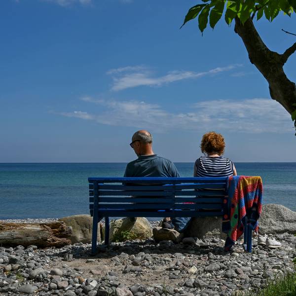 Ein Paar sitzt auf einer blauen Bank am Meer.