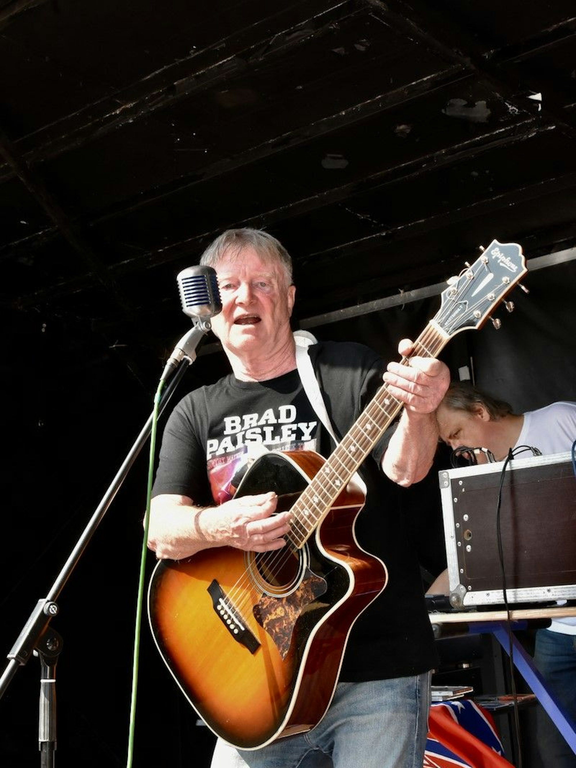 Ein Mann spielt Gitarre auf einer Bühne.