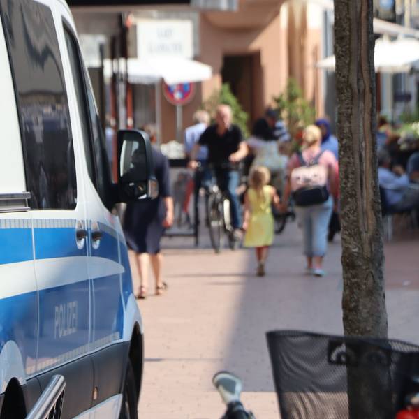 Ein Polizeiauto steht am Rand einer Fußgängerzone.