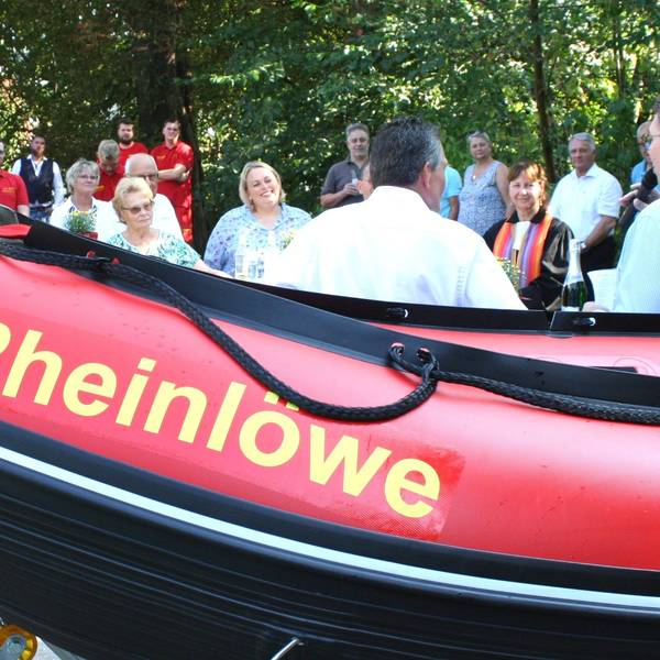 Männer und Frauen neben einem Schlauchboot.