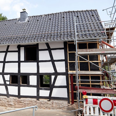 Das Bild zeigt eine Außenansicht des Gebäudes. Während man an vielen Stellen den Fortschritt sieht, steht rechts ein Gerüst.