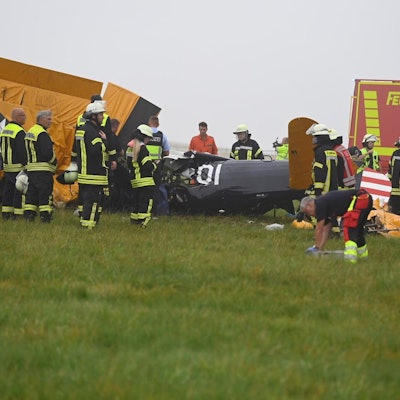 Das Wrack des Flugzeugs liegt auf einem Feld, umgeben von Feuerwehrleuten.