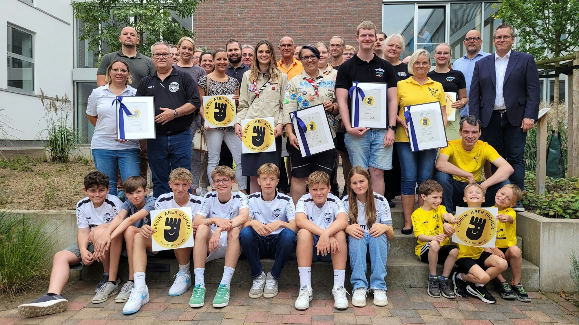 Kinder und Erwachsene halten eine Auszeichnung in den Händen.