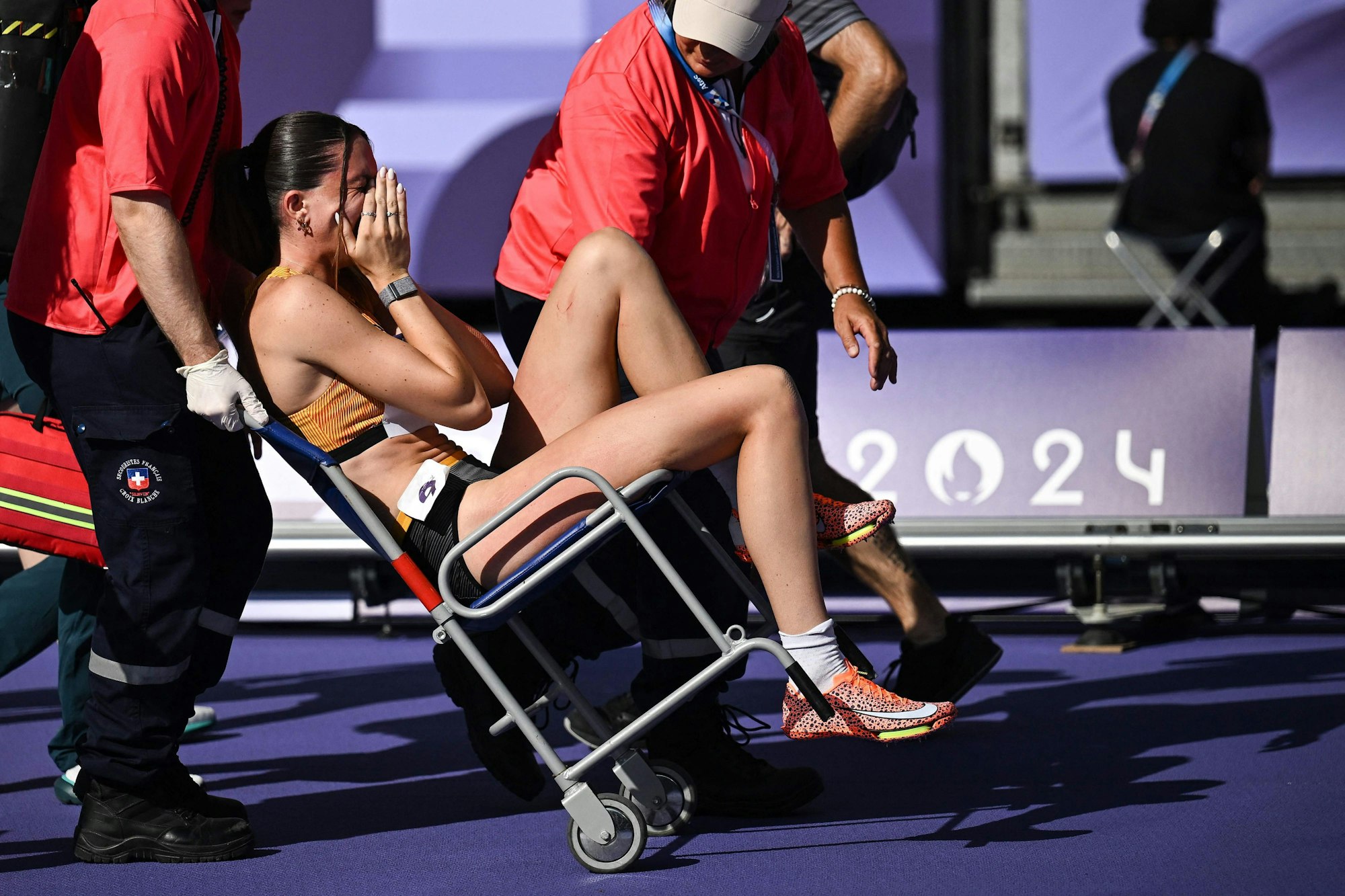 Medical staff take Germany's Sophie Weissenberg away from the track during the women's heptathlon 100m hurdles of the athletics event at the Paris 2024 Olympic Games at Stade de France in Saint-Denis, north of Paris, on August 8, 2024. (Photo by Ben STANSALL / AFP)