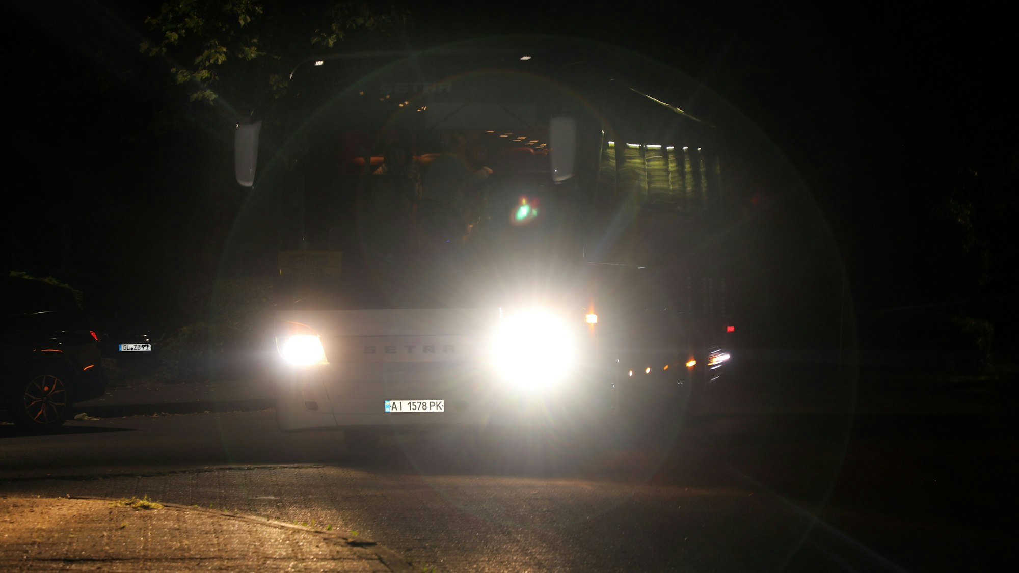 Ein Bus mit eingeschalteten Scheinwerfern fährt durch die Nacht.