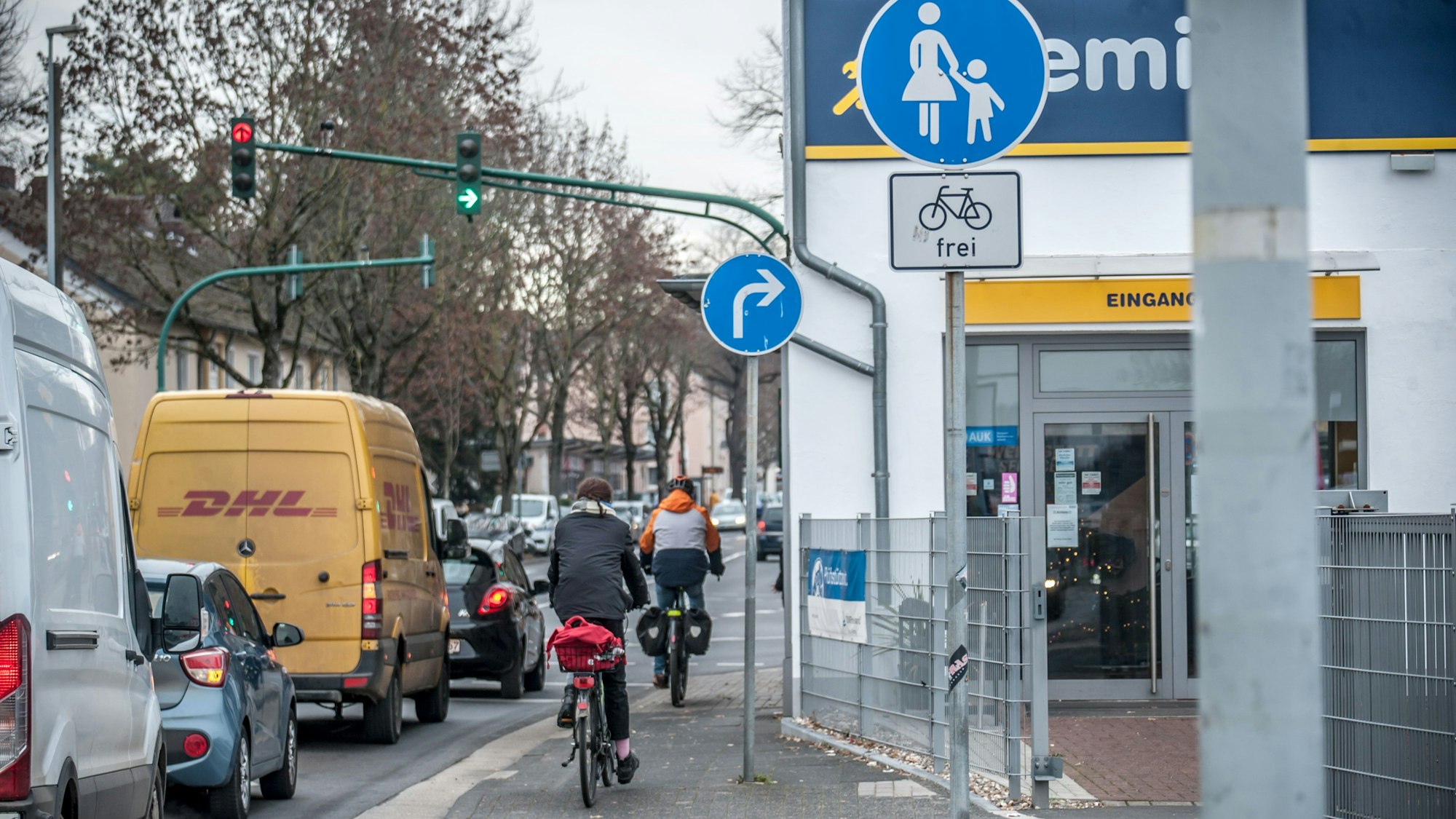 Radfahrer fahren auf einem engen Gehweg neben Autos her.