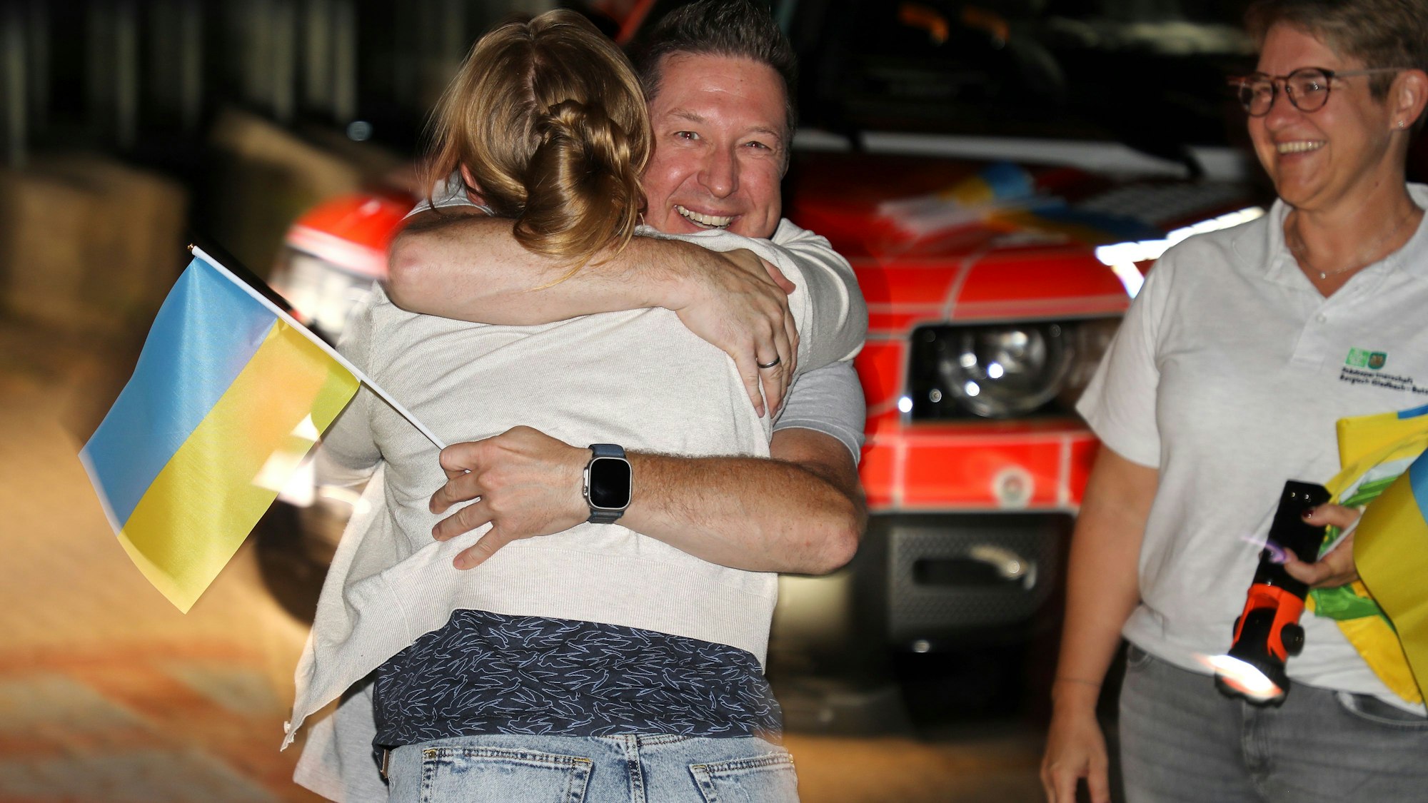 Menschen umarmen sich in der Nacht an der Gesamtschule in Bergisch Gladbach-Paffrath.