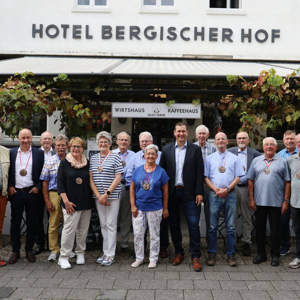 Eine Gruppe von Männer und Frauen vor der Terrasse eines Lokals.