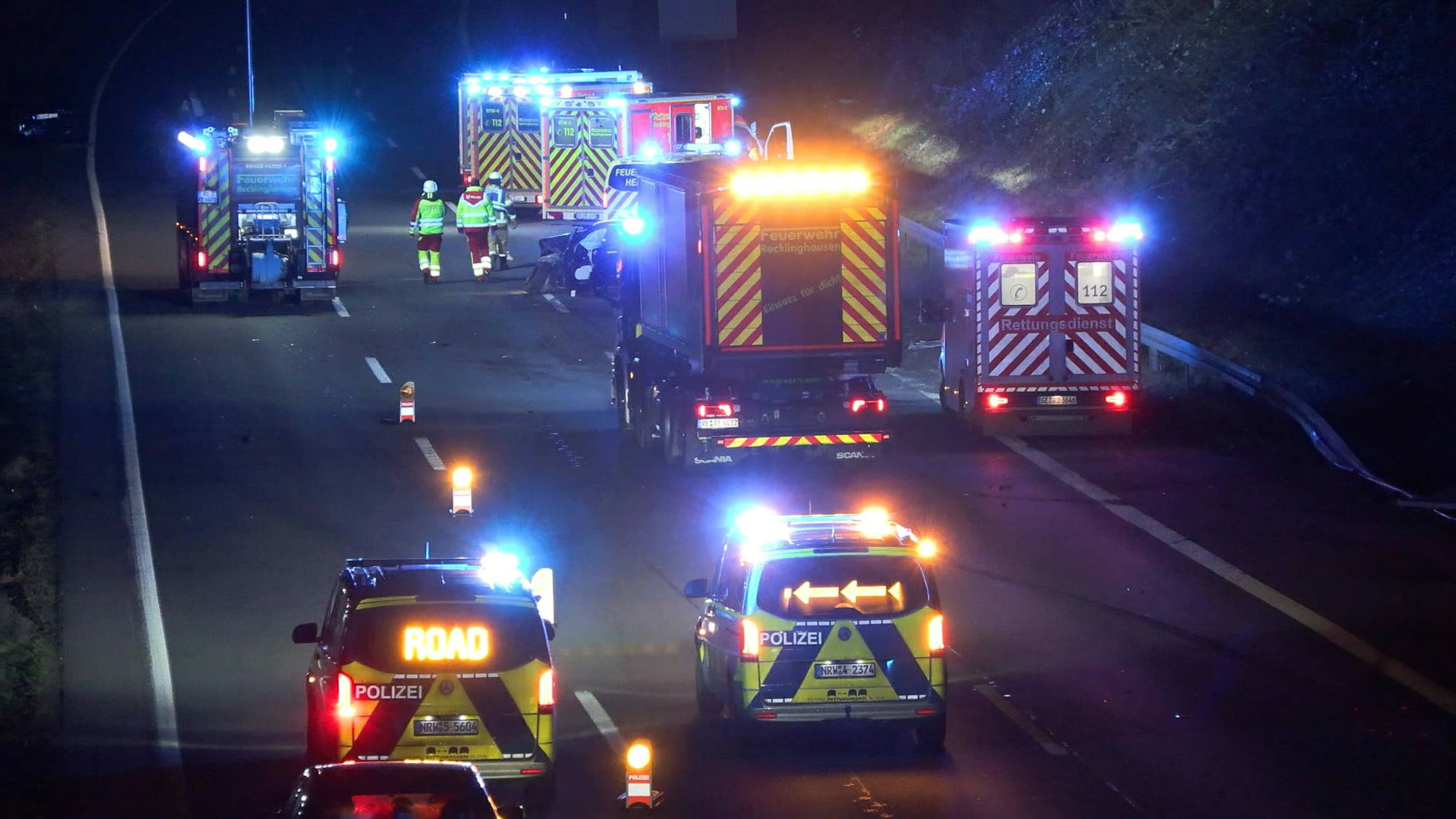 Polizeiautos mit Blaulicht stehen nachts auf einer Autobahn.