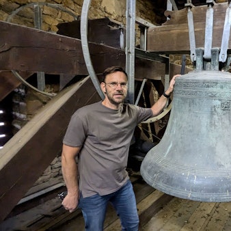 Ortsbürgermeister und Kirchenvorstand Björn Wassong steht in der Kirche in Mechernich-Weyer an der Cyriakus-Glocke von 1584.