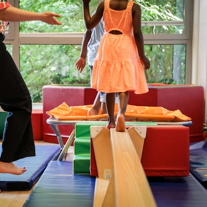 Ein Mädchen balanciert über eine umgedrehte Bank.