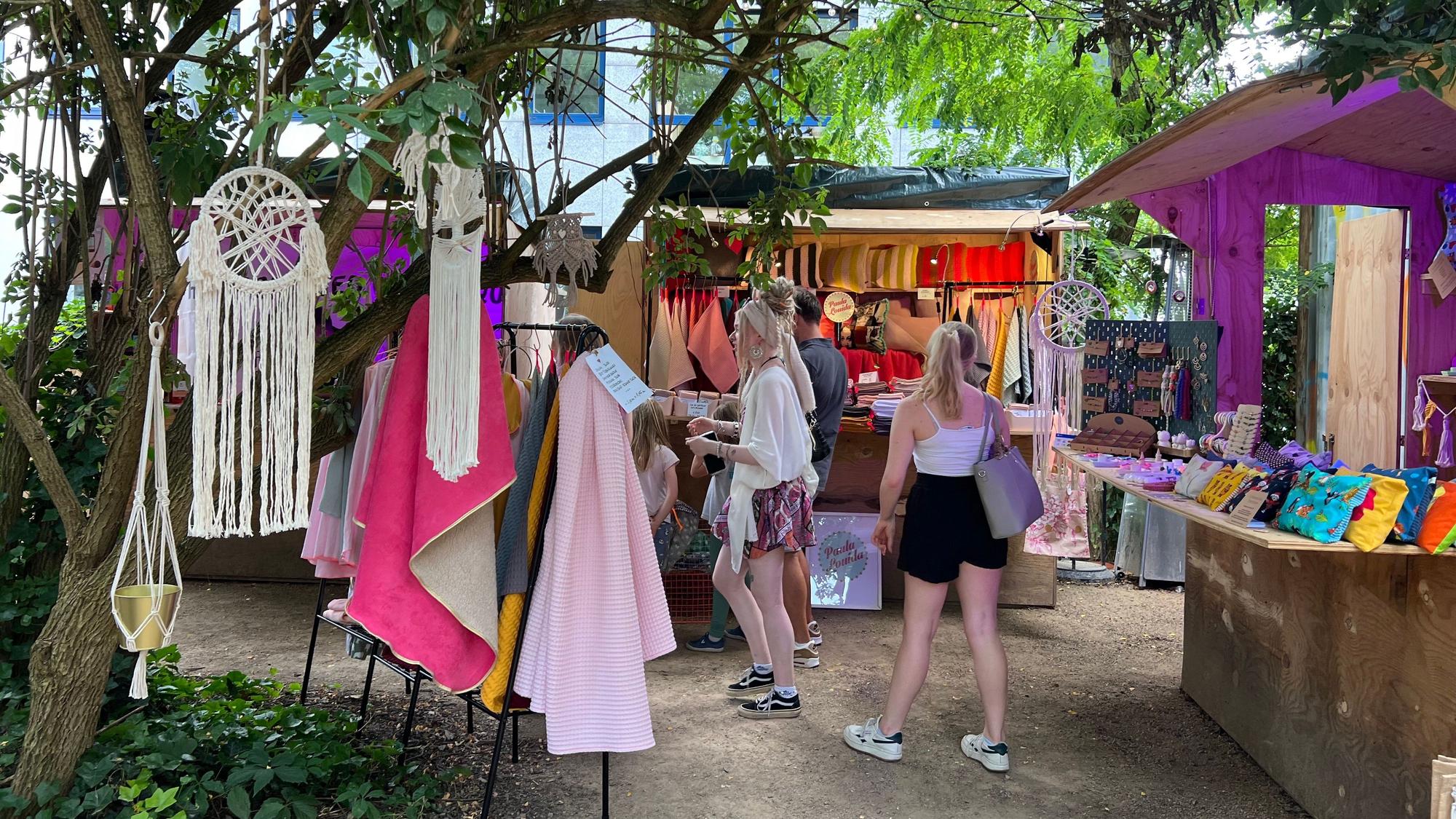 Besucherinnen vor Holzbuden auf einem Markt
