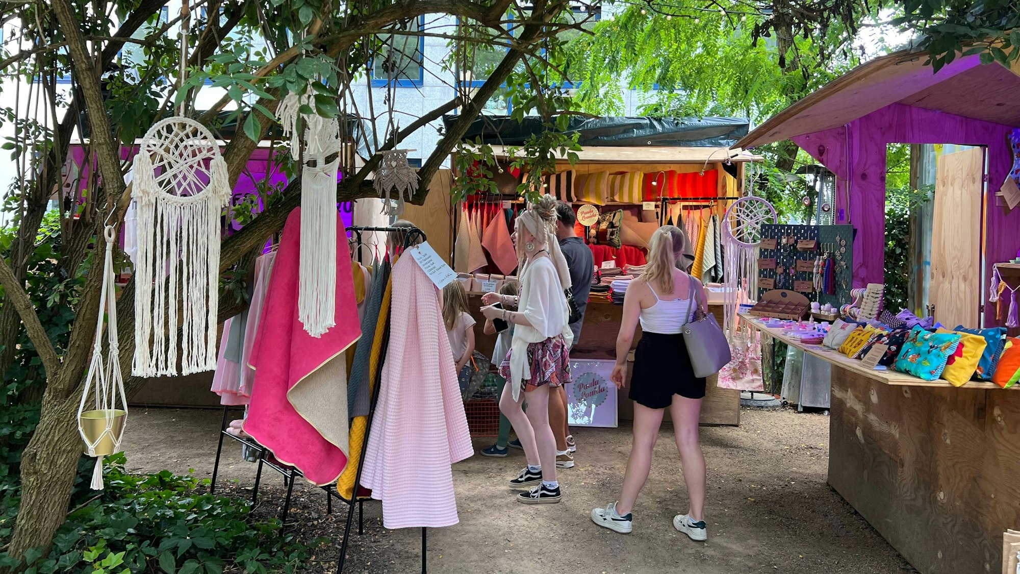 Besucherinnen vor Holzbuden auf einem Markt
