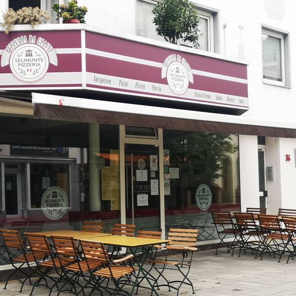 Die Pizzeria Selinunte Da Gianni in der Wesselinger Bahnhofstraße gehört zu den beliebtesten im Rhein-Erft-Kreis. Hier ist sie von außen zu sehen. Eine Jalousie ist eingefahren, draußen stehen Stühle und Tische.